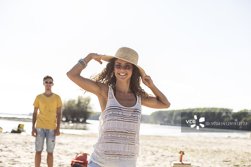 戴着遮阳帽对着镜头微笑的年轻女人图片素材