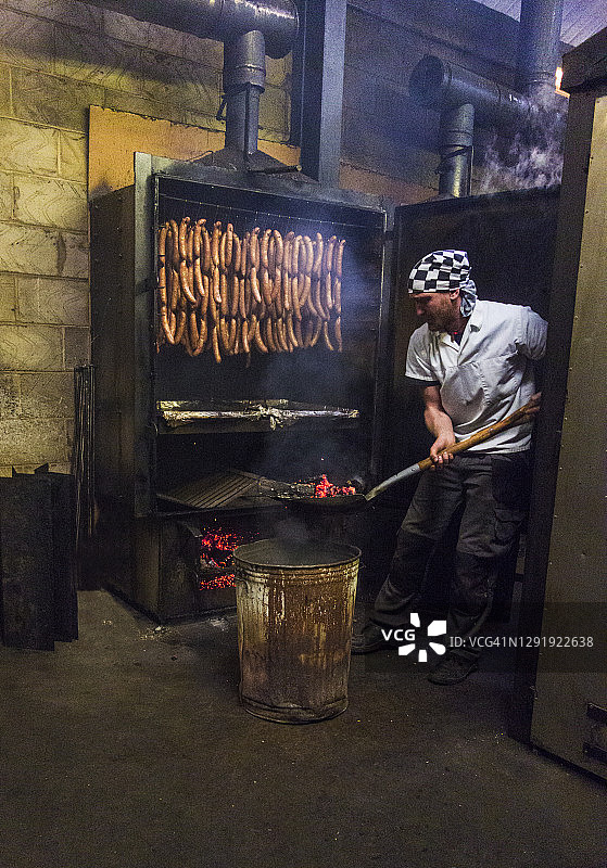 食品厂工人向熏房内添加煤炭，准备香肠图片素材