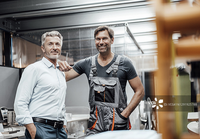 笑容满面的中年男工程师和工人在工业界查阅文件图片素材