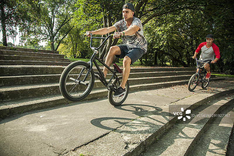 年轻男人在公园台阶上用BMX自行车做车轮特技图片素材