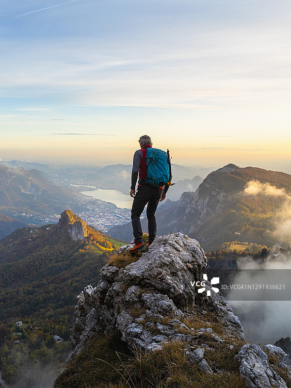 在意大利贝加莫阿尔卑斯山日出时站在山顶的沉思徒步旅行者图片素材