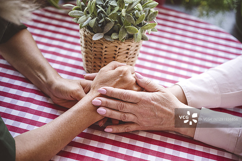 女人们在餐厅的桌旁手牵着手图片素材