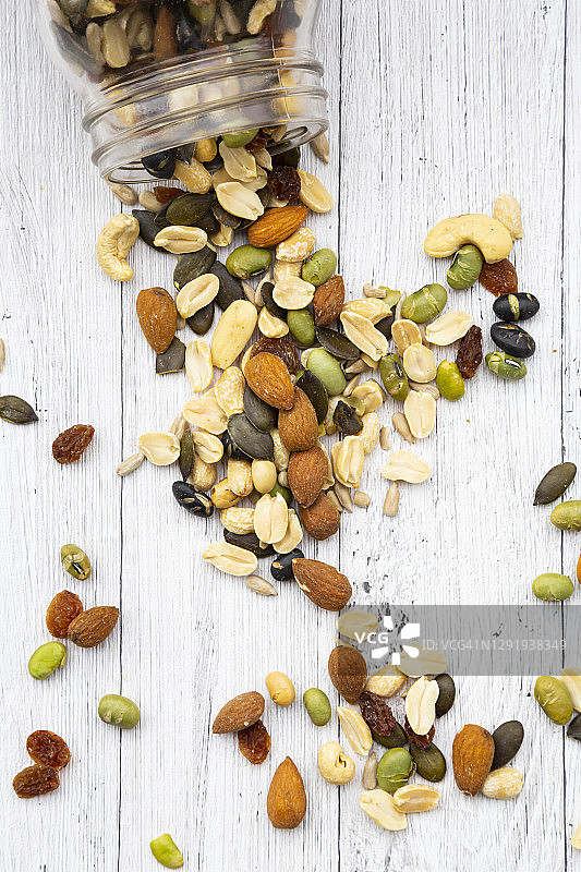 木质背景上散落的葡萄干坚果种子罐图片素材