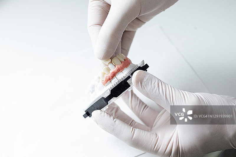 诊所里医生拿着牙冠和假牙的特写镜头图片素材