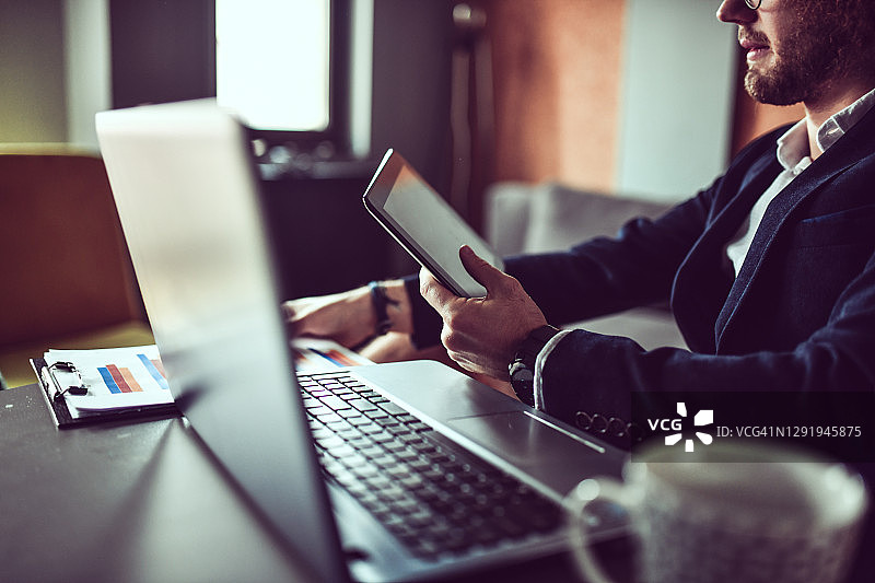 男商人使用数位平板电脑和笔记本电脑分析图表图片素材