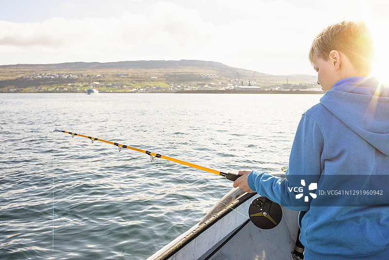 青少年在船上用鱼竿钓鱼图片素材
