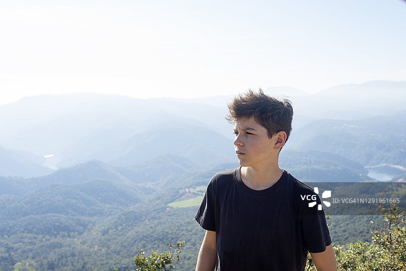身穿黑色T恤的年轻男子站在山前图片素材
