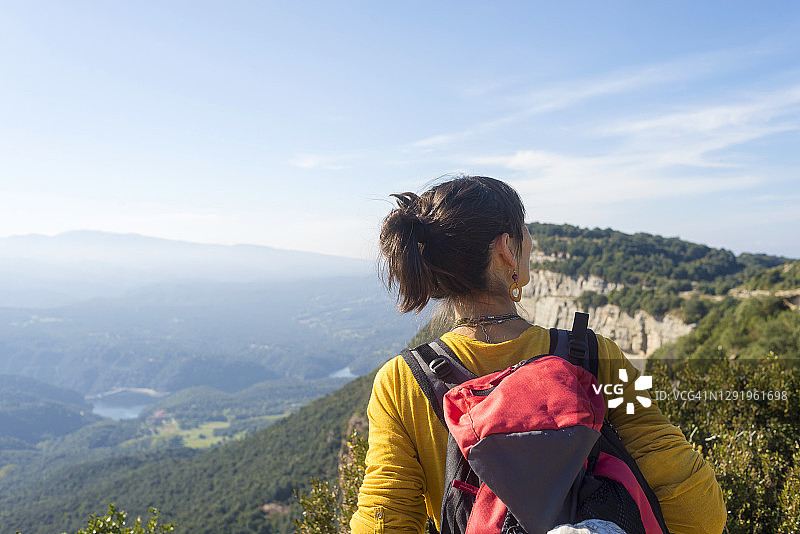 站在高山上欣赏风景的年轻女子背影图片素材