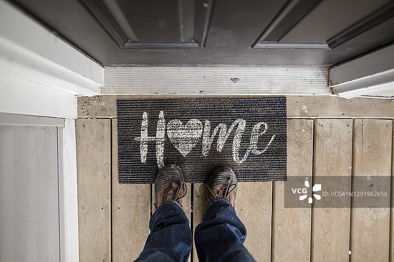 站在家门口的脚垫上的人的特写图片素材