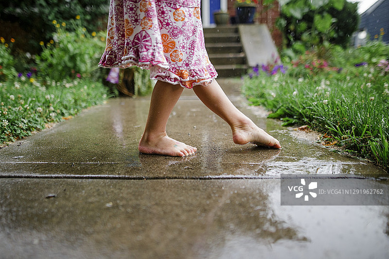 赤脚儿童在雨中台阶上跳舞的特写图片素材