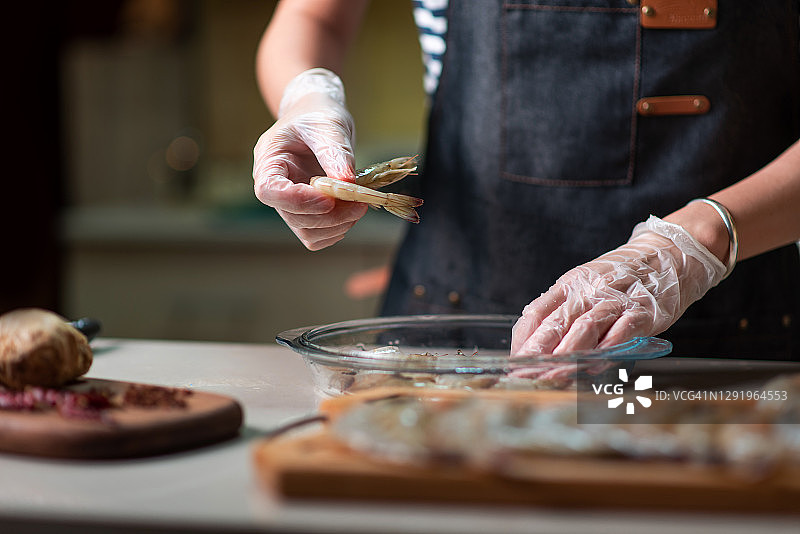 女人在玻璃碗中挑选鲜虾准备烹饪图片素材