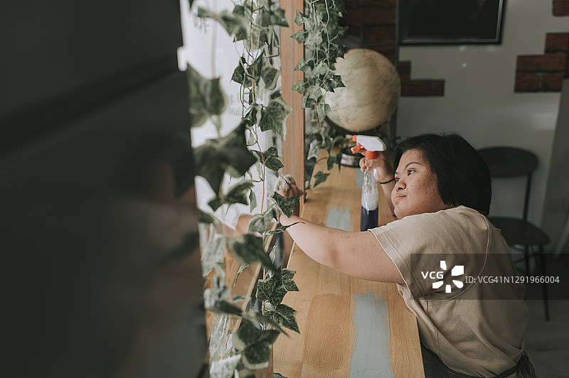 患有唐氏综合征的亚洲女服务员在咖啡馆清洁窗户图片素材