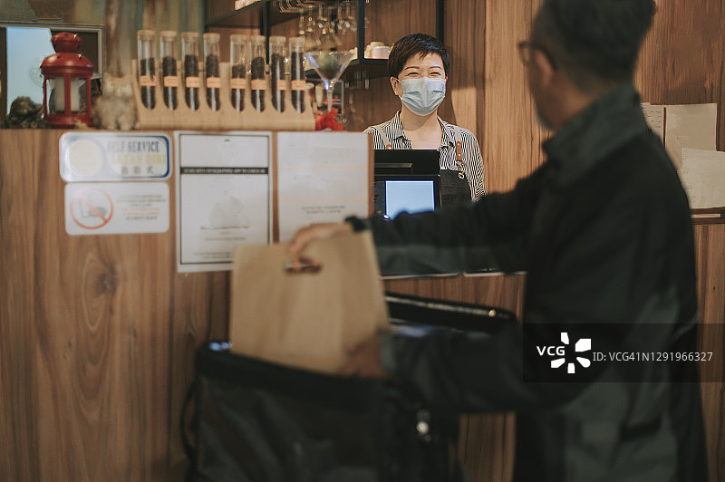 亚洲华人老年男子送外卖，在咖啡馆取餐并放入保温箱图片素材