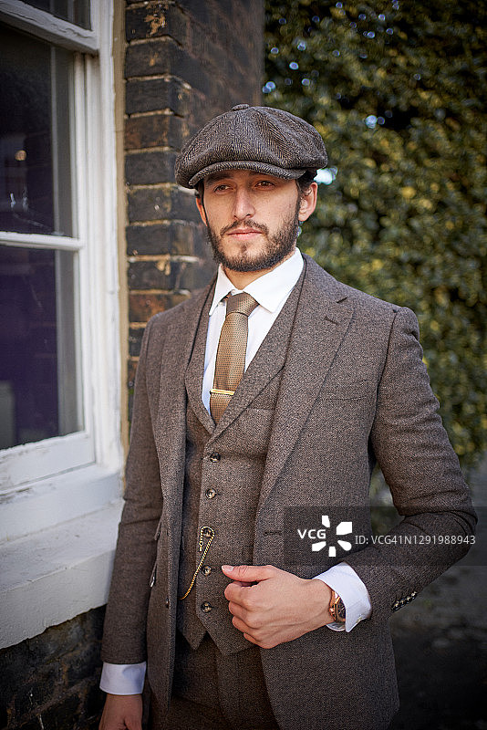 戴粗花呢西装和鸭舌帽的酷男人图片素材
