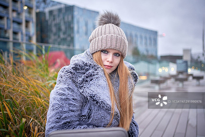 冬天，年轻女子坐在户外看着镜头图片素材