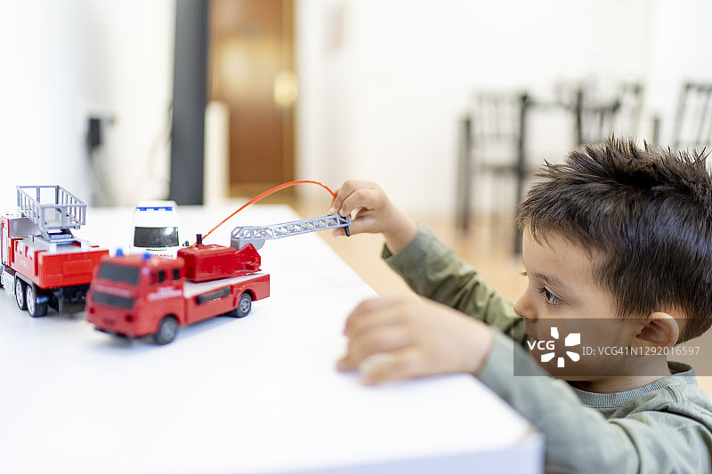 男孩在家玩消防车玩具图片素材