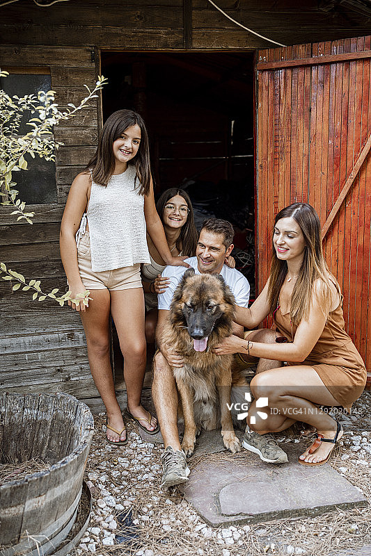 在后院度假时，带着宠物狗站在门口的家庭图片素材