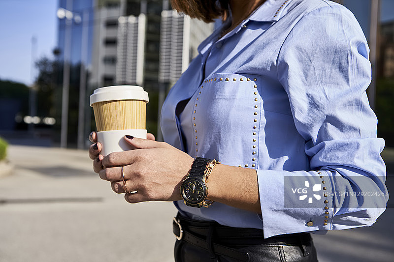 在晴天拿着竹制咖啡杯在街上的女人图片素材