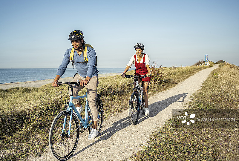 情侣在晴朗的天空下骑自行车图片素材