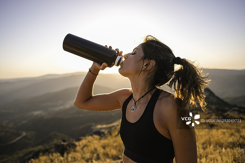 年轻女运动员喝瓶装水的特写图片素材