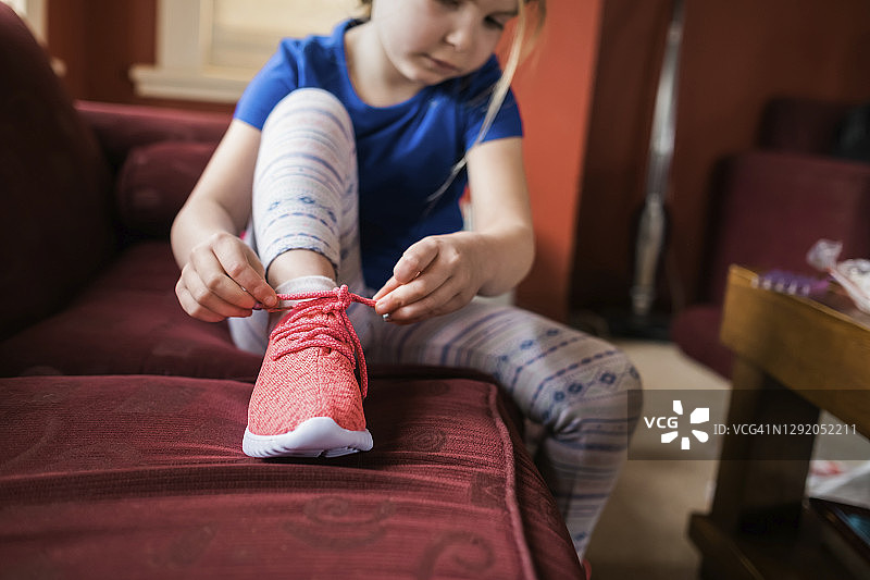 坐在沙发上系鞋带的年轻女孩图片素材