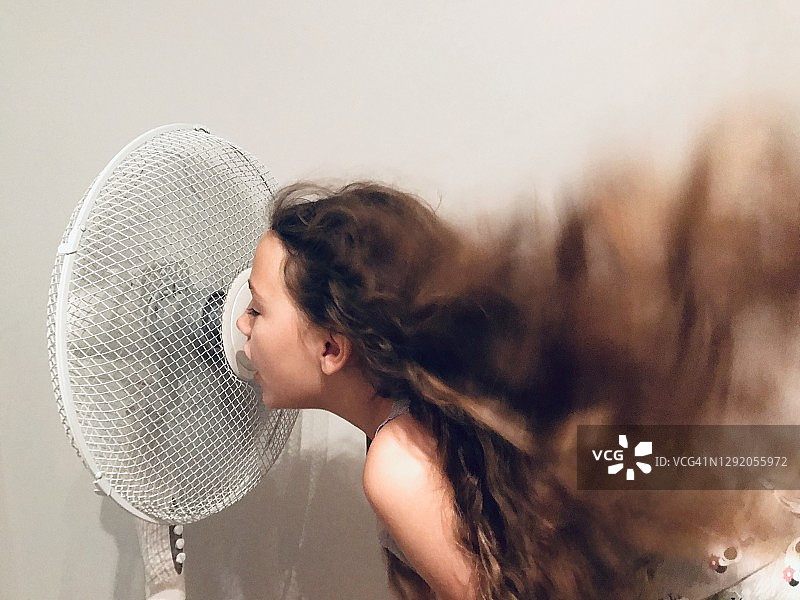 站在风扇前乘凉的长发女孩图片素材