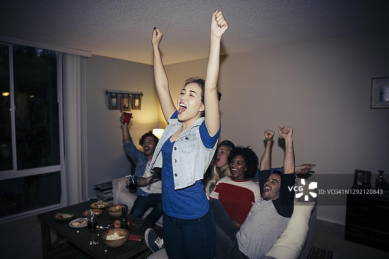 朋友们在家看电视体育节目时欢呼图片素材