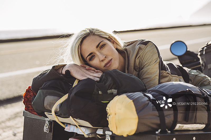 靠在路边摩托车上的年轻女子肖像图片素材