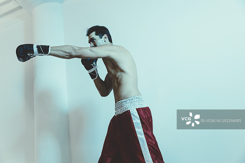 拳击手在白墙边练习出拳的低角度景观图片素材