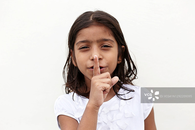 6-7岁女孩用食指放在嘴唇上图片素材