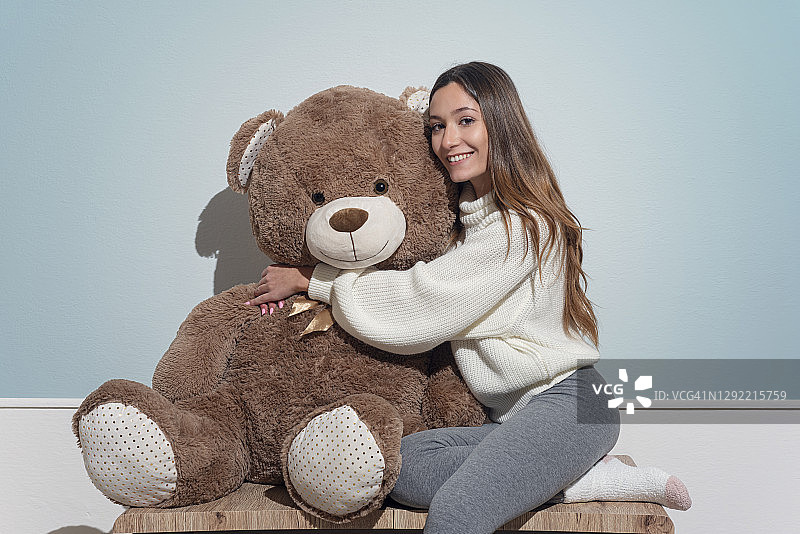 抱着大泰迪熊的年轻女人图片素材