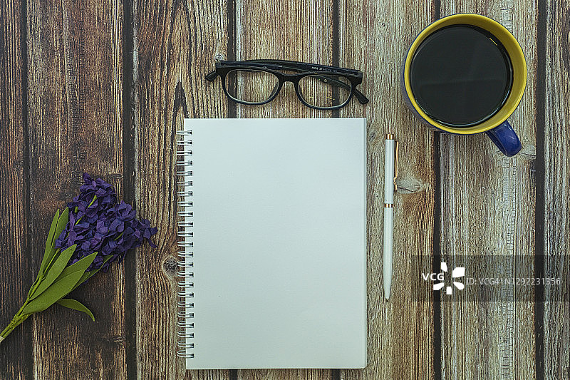 木桌上的空白记事本、眼镜、咖啡杯和鲜花，概念和背景图片素材
