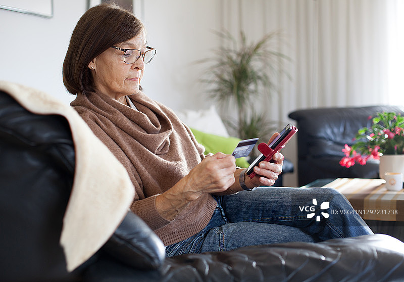 年长的女人用信用卡和智能手机在线购物图片素材