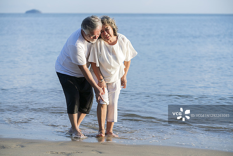 中年男子帮助受伤的中年妇女在海滩放松图片素材