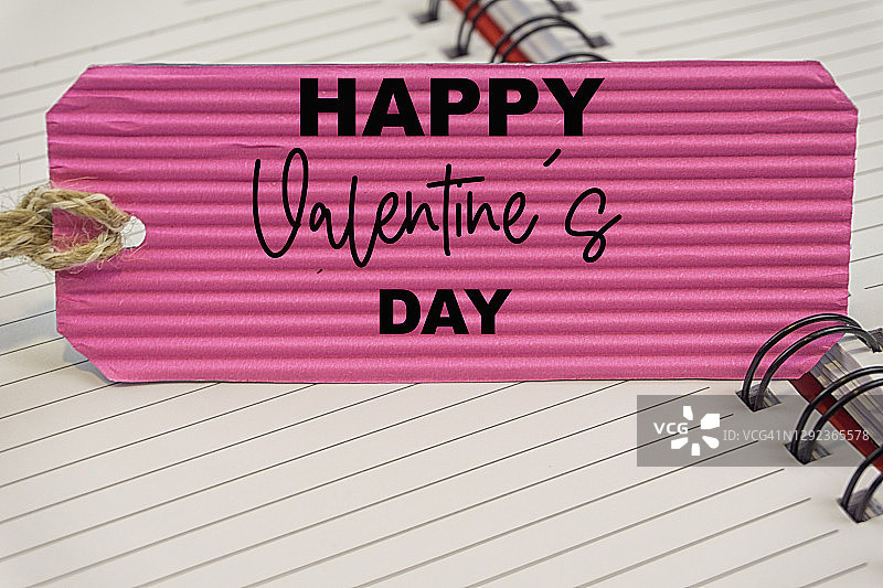 粉色促销标签上的情人节快乐字样与空白笔记本图片素材