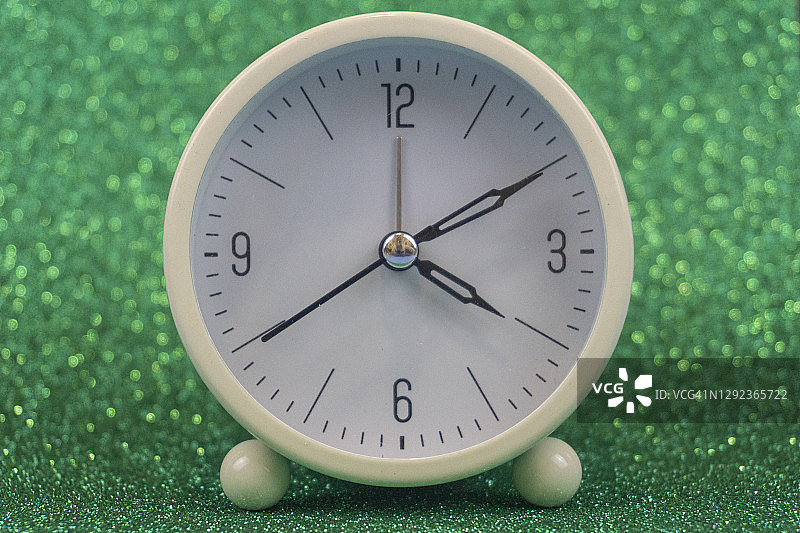 白色桌子或闹钟，绿色散景背景图片素材