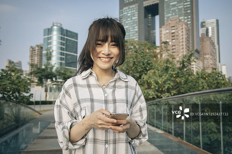 亚洲女性在城市街道上使用智能手机图片素材