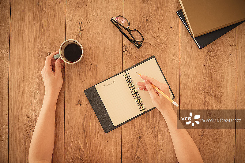 手在笔记本上写作并端着一杯咖啡图片素材