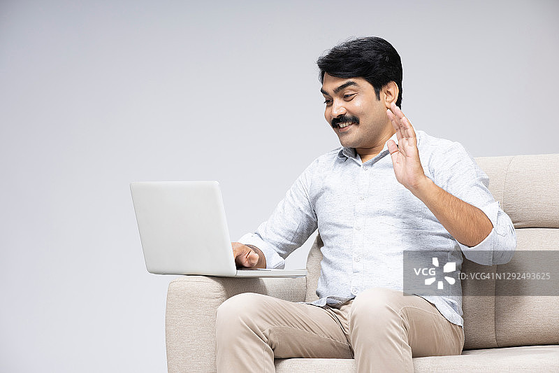 年长的男人坐在白色背景的沙发上，库存照片图片素材