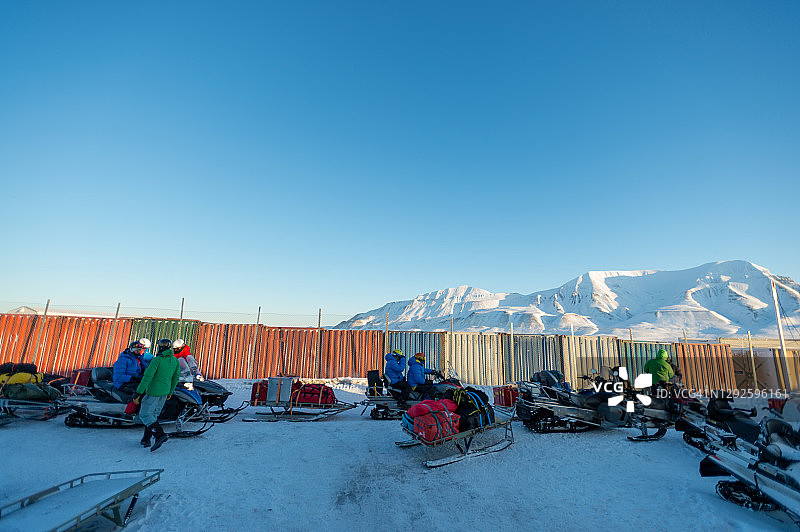一群雪地摩托车手准备在黎明时离开城镇图片素材
