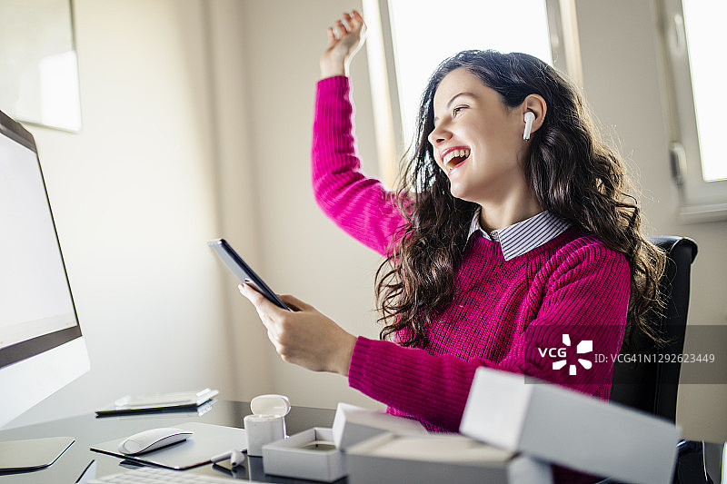 快乐的女商人享受在办公室里她最喜欢的歌曲图片素材
