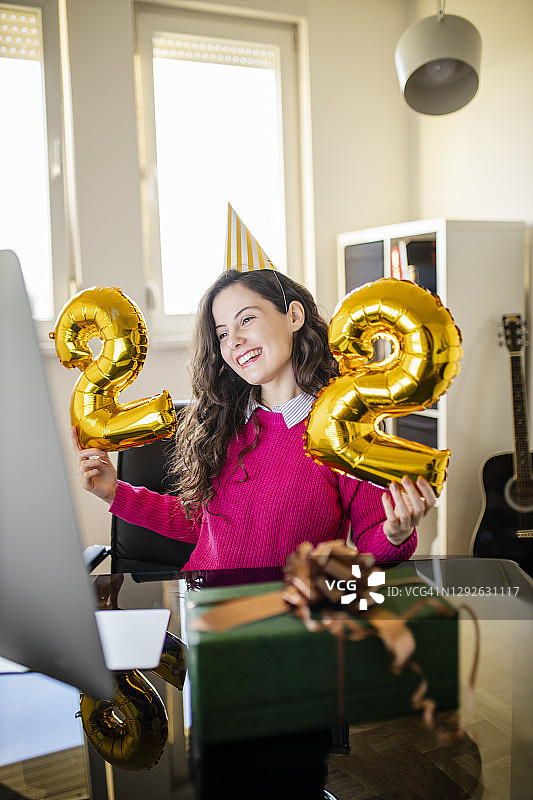 疫情隔离期间在家中与朋友视频通话庆祝生日的女人图片素材