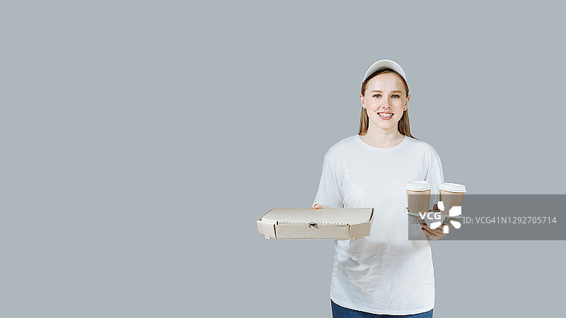 送披萨和咖啡的送货员。灰色背景。食品、商品从商店和餐厅送货上门的概念。文案空间图片素材