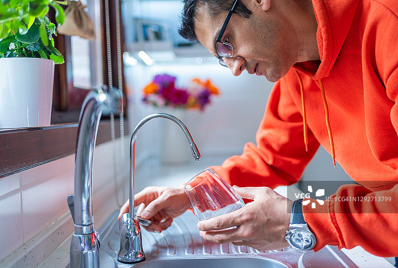 干旱缺水危机：年轻人焦急等待水龙头滴水图片素材