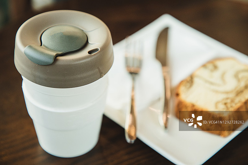 可重复使用杯中的咖啡和盘中的蛋糕图片素材