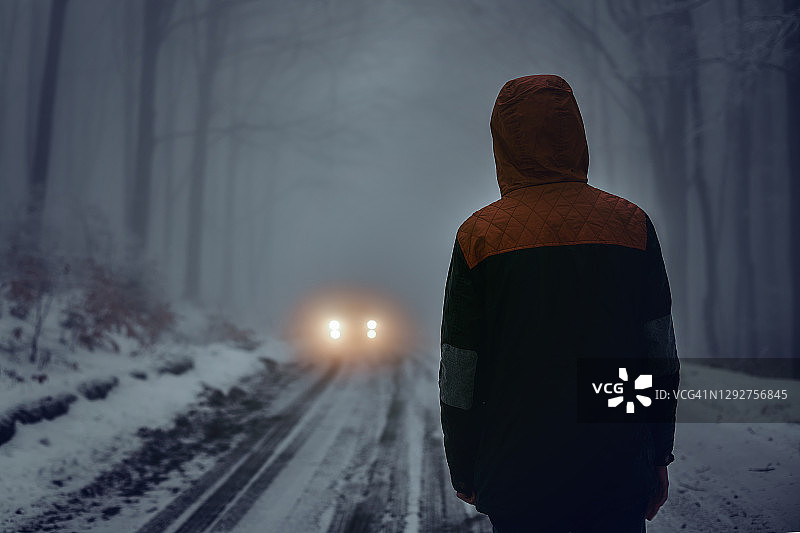 雾蒙蒙的冬日道路上戴着帽子的少年图片素材