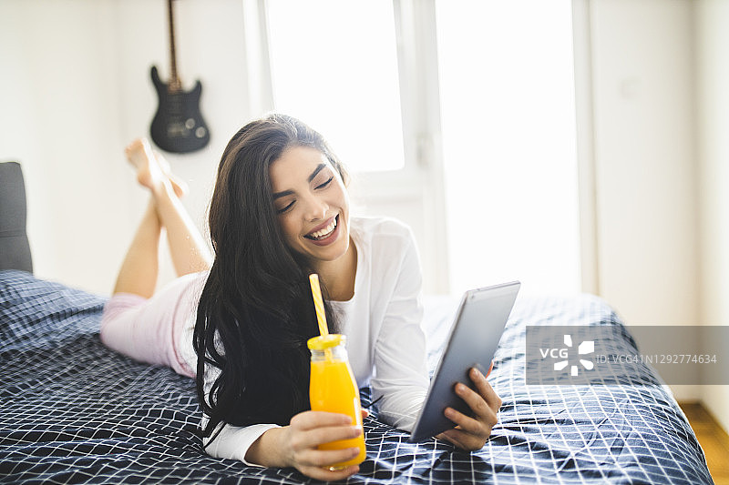 快乐的女人在早晨阅读报纸、喝果汁图片素材