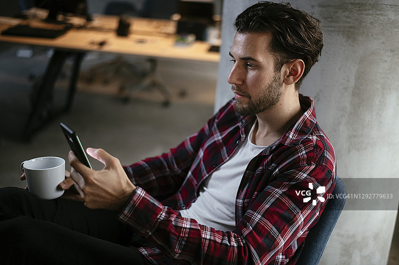 商人一边喝咖啡一边使用手机图片素材