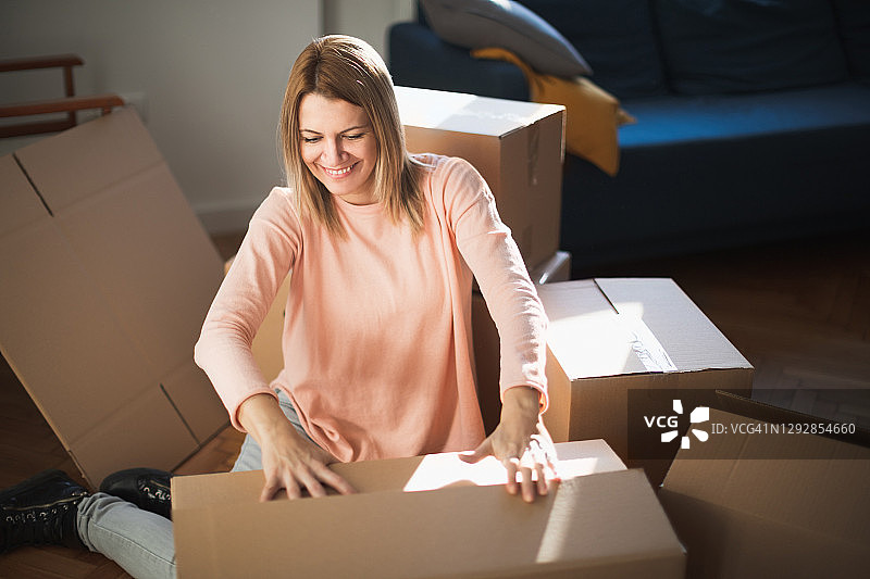 快乐的女人正在关闭纸板箱，准备搬家图片素材