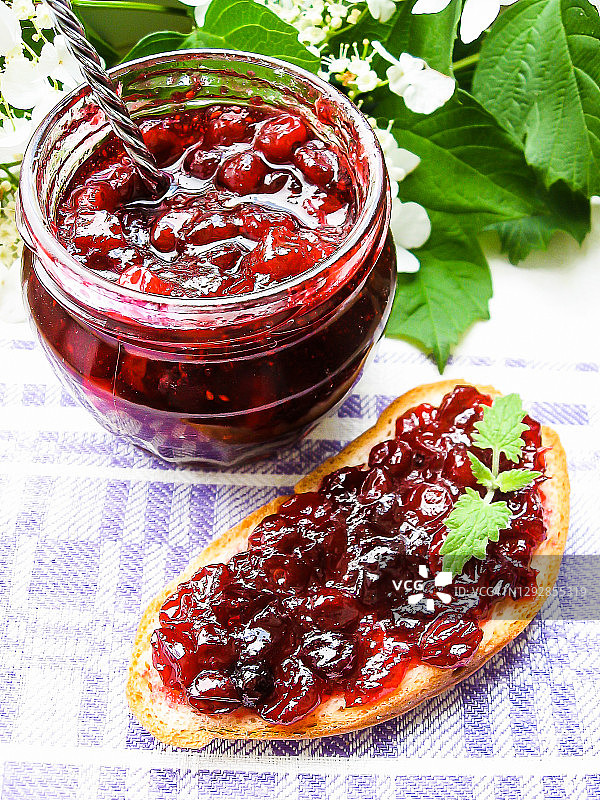 罐装蔓越莓酱或酱汁，以及一块涂有蔓越莓酱的早餐面包图片素材